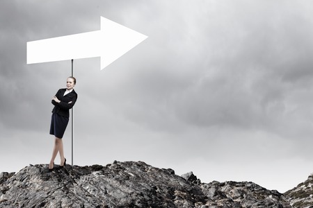 Young businesswoman leaning on arrow blank banner signの写真素材