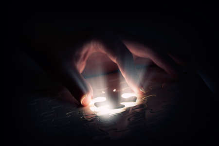 Hand connecting missing jigsaw glowing puzzle pieceの写真素材