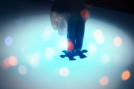 Hand connecting two jigsaw glowing puzzle piecesの写真素材