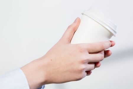 Close up of man's hands standing at balcony with plastic cupの写真素材