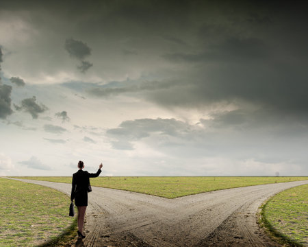 Back view of businesswoman standing on crossroads and making choiceの写真素材