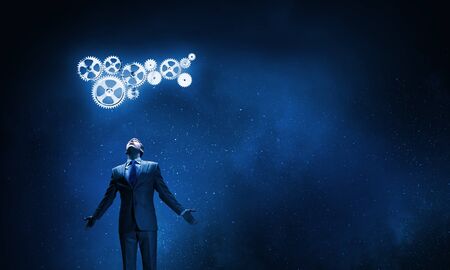 Businessman with hands spread apart looking above at gears mechanismの写真素材