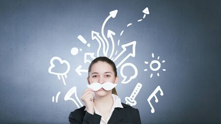 Happy cute girl trying male paper mustacheの写真素材