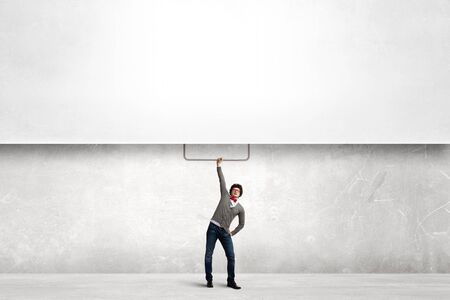 Young man in casual pulling blank banner. Place for textの写真素材