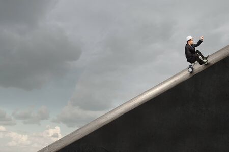 Young funny businessman riding three wheeled bicycleの写真素材