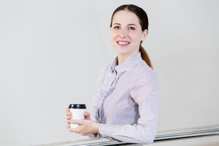 Casual caucasian woman standing at balcony with coffee in handsの写真素材