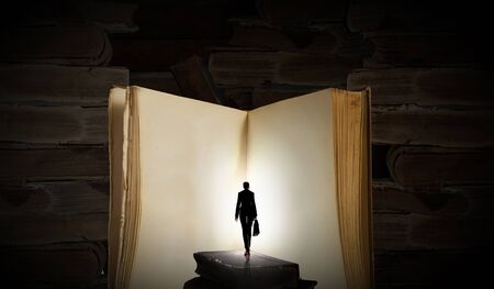 Big old opened book and miniature of businesswomanの写真素材