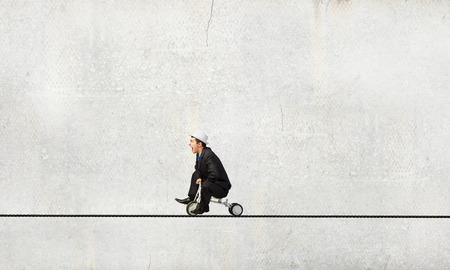 Young funny businessman riding three wheeled bicycleの写真素材
