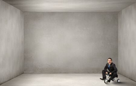 Young funny businessman riding three wheeled bicycleの写真素材