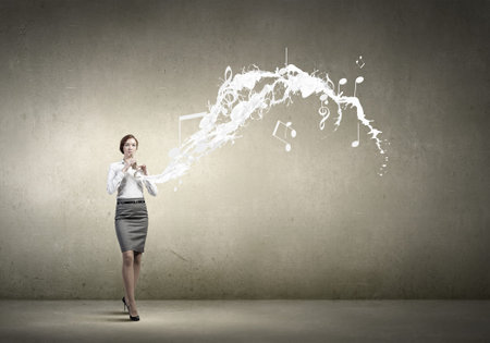 Cheerful businesswoman playing fife on color backgroundの写真素材