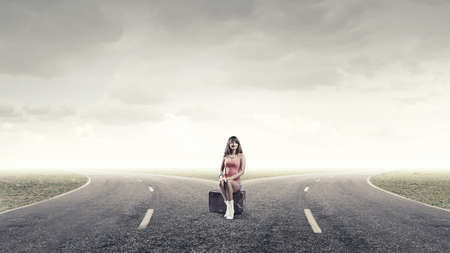 Young retro woman waiting on road with her vintage baggageの写真素材