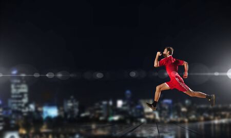 Running man in red sport wear on dark backgroundの写真素材