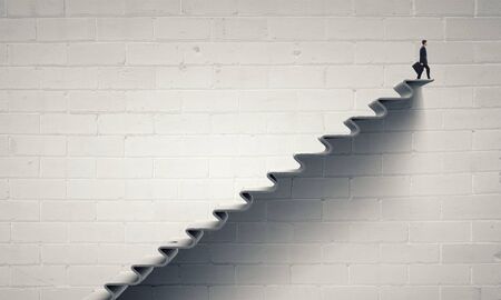 Young businessman on staircase top representing success conceptの写真素材