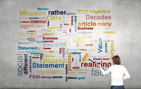 Young businessman standing with back and writing different words on wallの写真素材