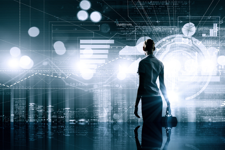 Rear view of businesswoman with suitcase and diagrams on virtual panelの写真素材