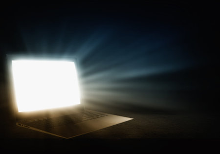 Open laptop with light coming from screen on dark backgroundの写真素材