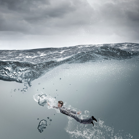 Young businessman in suit swimming in stormy watersの写真素材