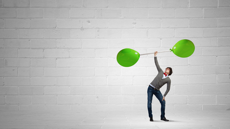 Confident businessman lifting above head barbell with balloonsの写真素材