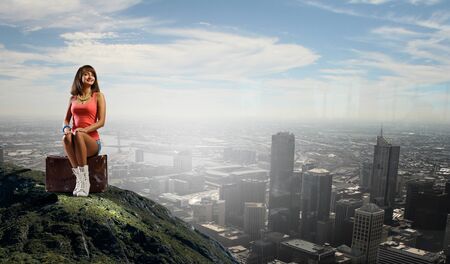 Young retro woman sitting on her vintage baggageの写真素材