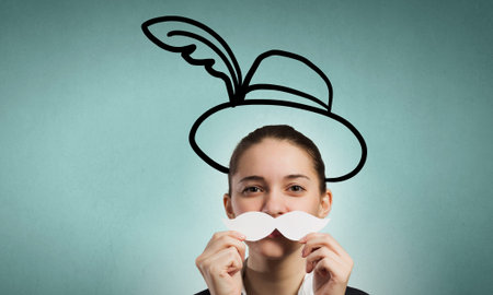 Happy cute girl trying male paper mustacheの写真素材