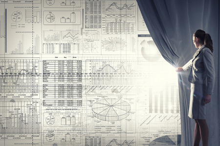 Young businesswoman opening curtain and presenting sales reportの写真素材