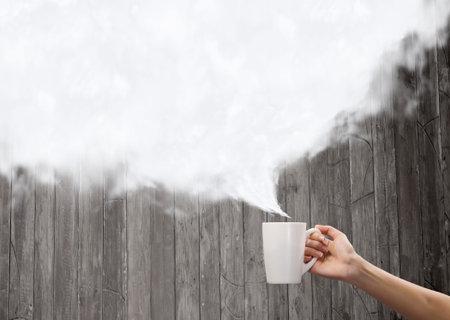 Close up of hand holding white mug of tea or coffeeの写真素材