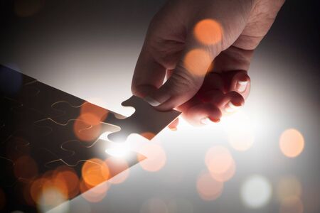Hand connecting missing jigsaw glowing puzzle pieceの写真素材