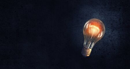 Glowing glass light bulb on dark bakgroundの写真素材