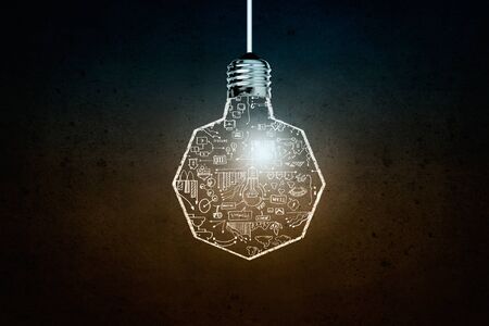 Glowing light bulb on dark background hanging from aboveの写真素材