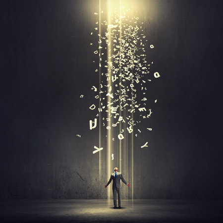 Businessman with hands spread apart standing in light coming from aboveの写真素材
