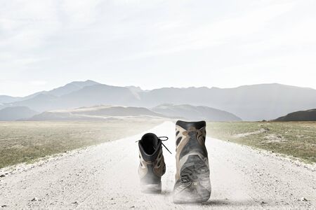 Pair of hikers boots walking on roadの写真素材