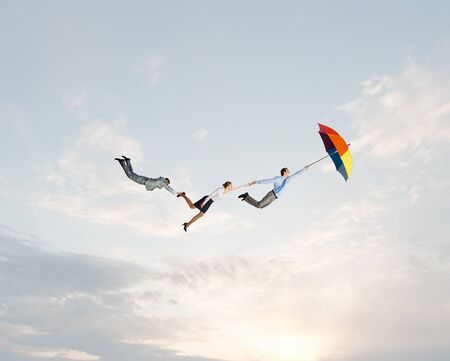 Business people flying in the sky on umbrellaの写真素材