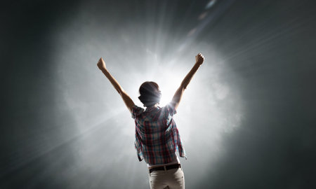 Rear view of woman with hands up facing success
