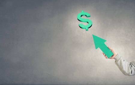 Hand of businessman holding arrow and pointing at dollar signの写真素材
