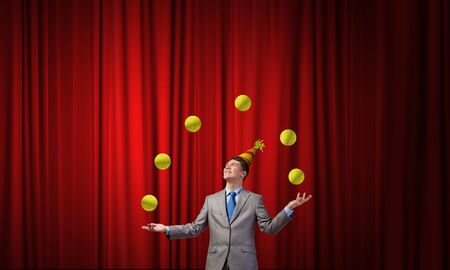Young businessman in cap on stage juggling with ballsの写真素材