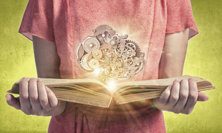 Young woman in red dress with book in hands and gears mechanism in airの写真素材