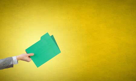 Hand of business person holding folder in raised handの写真素材
