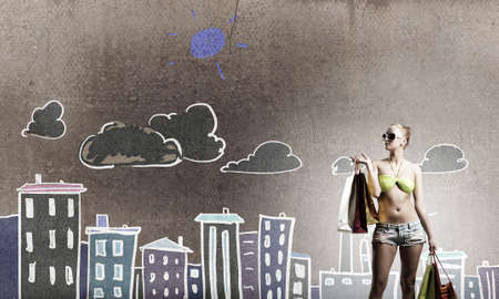 Young pretty woman in bikini and shorts with shopping bagsの写真素材