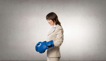 Young businesswoman in blue boxing gloves competition readyの写真素材