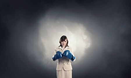 Young confident businesswoman wearing blue boxing glovesの写真素材