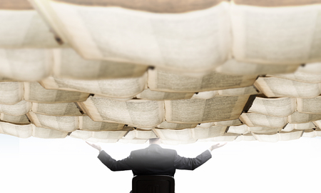 Rear view of businessman and sky of books above his headの写真素材