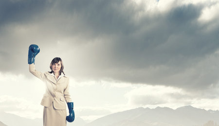 Young confident businesswoman wearing blue boxing glovesの写真素材