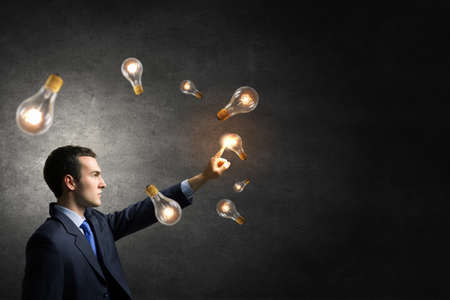 Businessman reaching hand to touch glass light bulbの写真素材