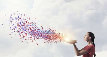 Young emotional woman in red dress with book in handsの写真素材