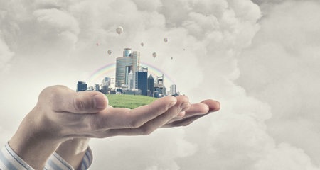 Close up of hands holding image of modern cityscapeの写真素材