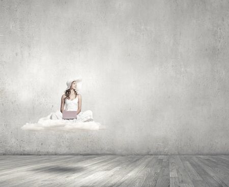 Young lady sitting on cloud with laptop on kneesの写真素材