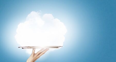 Human hand holding metal tray with cloudの写真素材