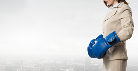 Young businesswoman in blue boxing gloves competition readyの写真素材