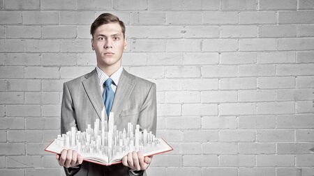 Businessman holding opened book with construction model on pagesの写真素材