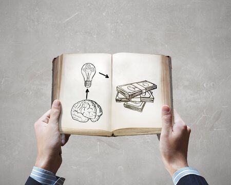 Opened book in male hands with financial ideas on pagesの写真素材